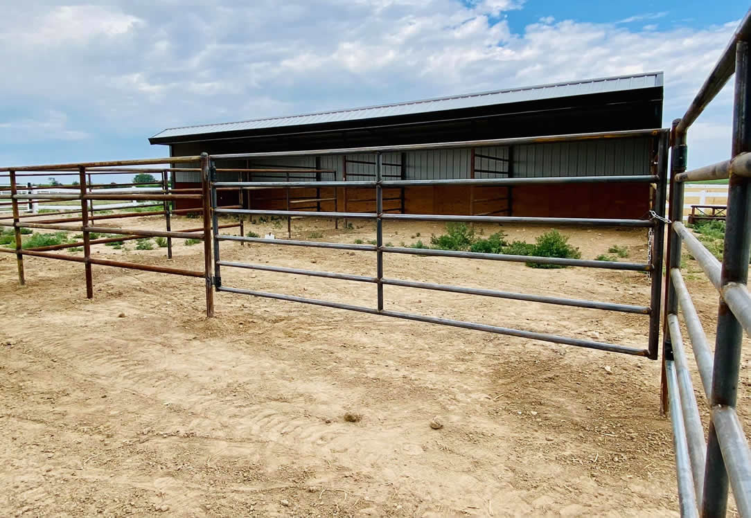 Pipe and Cable Fencing for a Riding Arena, complete with double gates and a custom flagpole. Construction by Integrity Welding Service LLC, servicing the Front Range of Colorado.